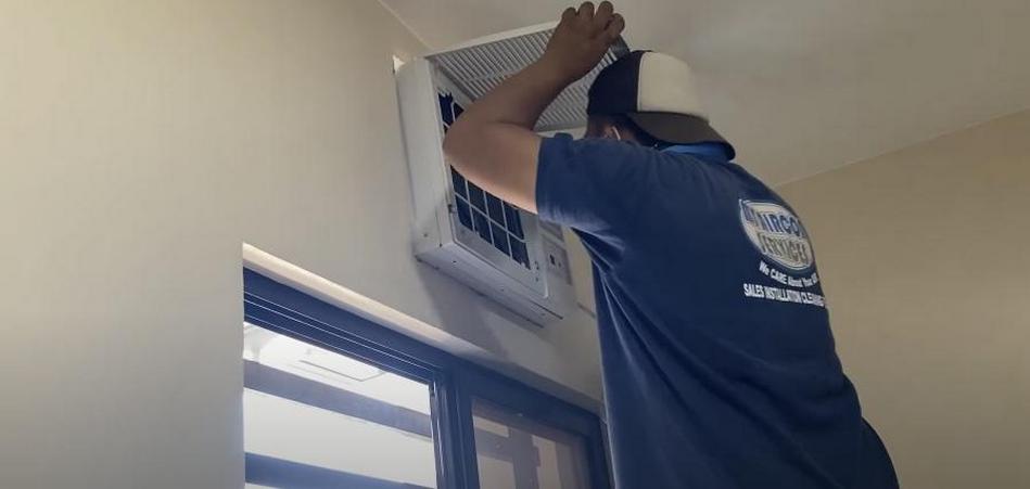 Man installing a window-type air conditioner.