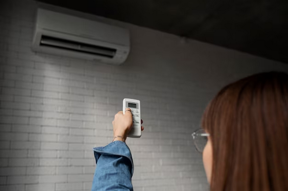 Woman using a remote control for an air conditioner.